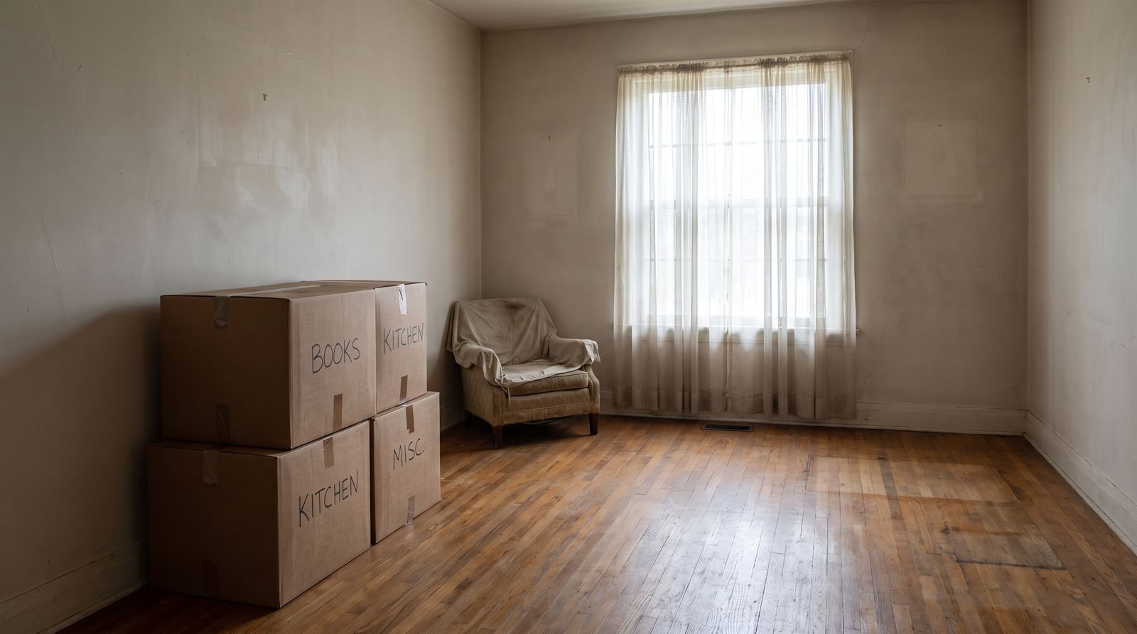 An almost empty living room with labeled boxes stacked during an estate cleanout